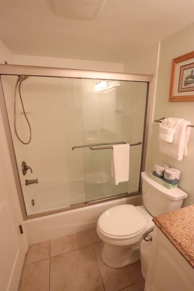 Finished bathroom with glass shower door and staged towels