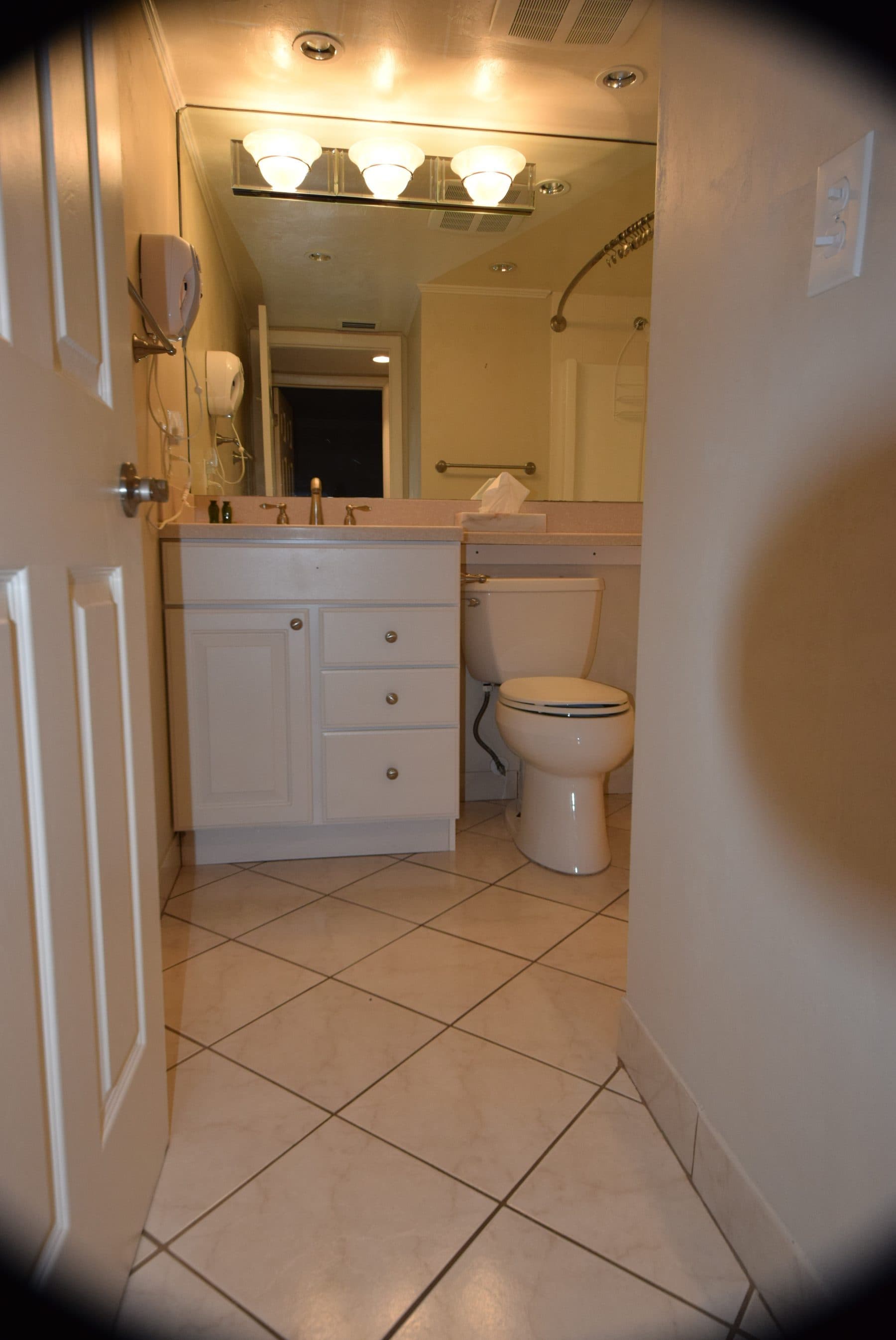 Dated bathroom with tan tile and floral curtain