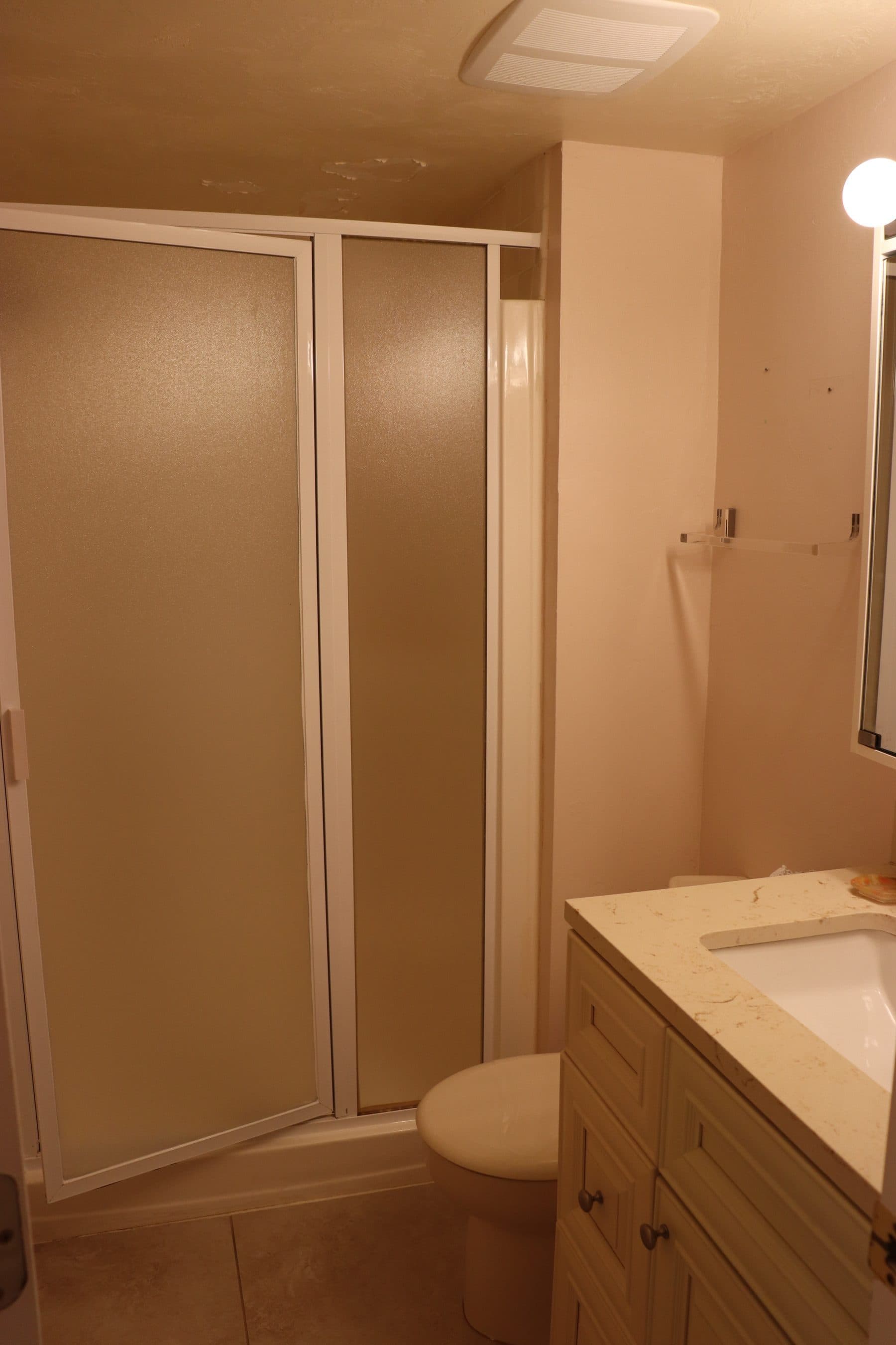 Dated bathroom with tan sliding shower doors and vanity
