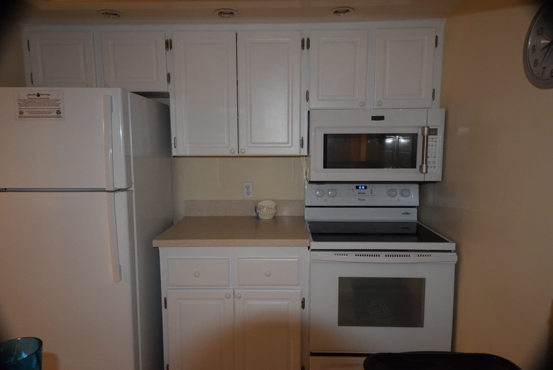 Dated kitchen with white cabinetry and appliances