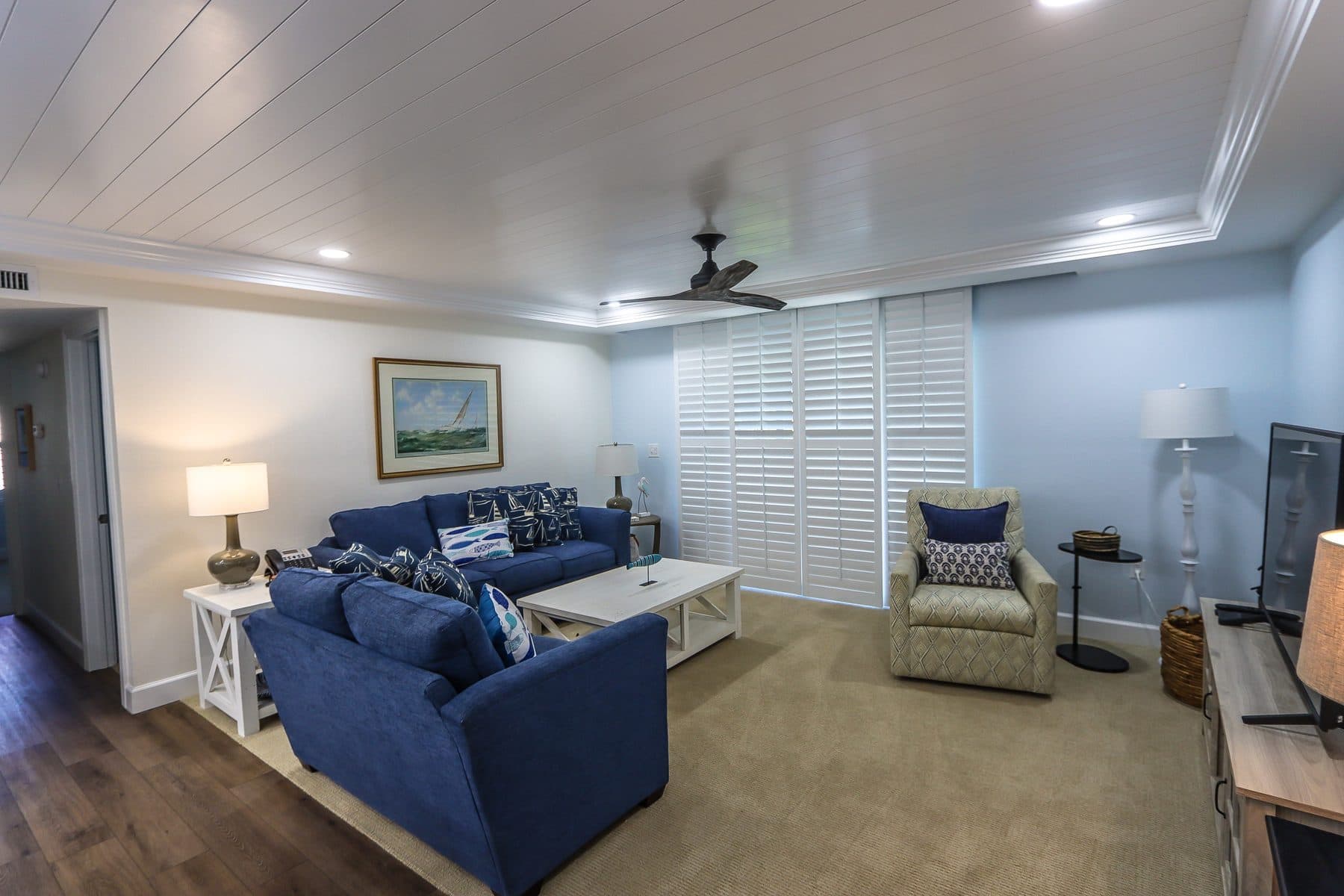 Finished living room with shiplap ceiling and blue sofas